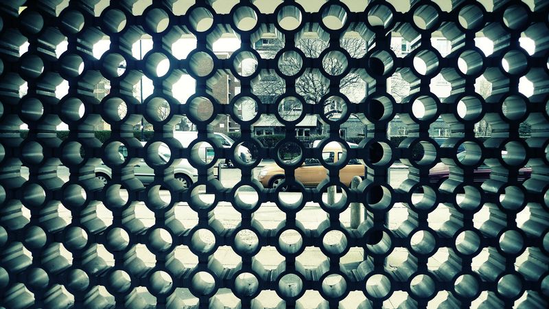 A photo of a London street obscured by a brutalist, concrete lattice